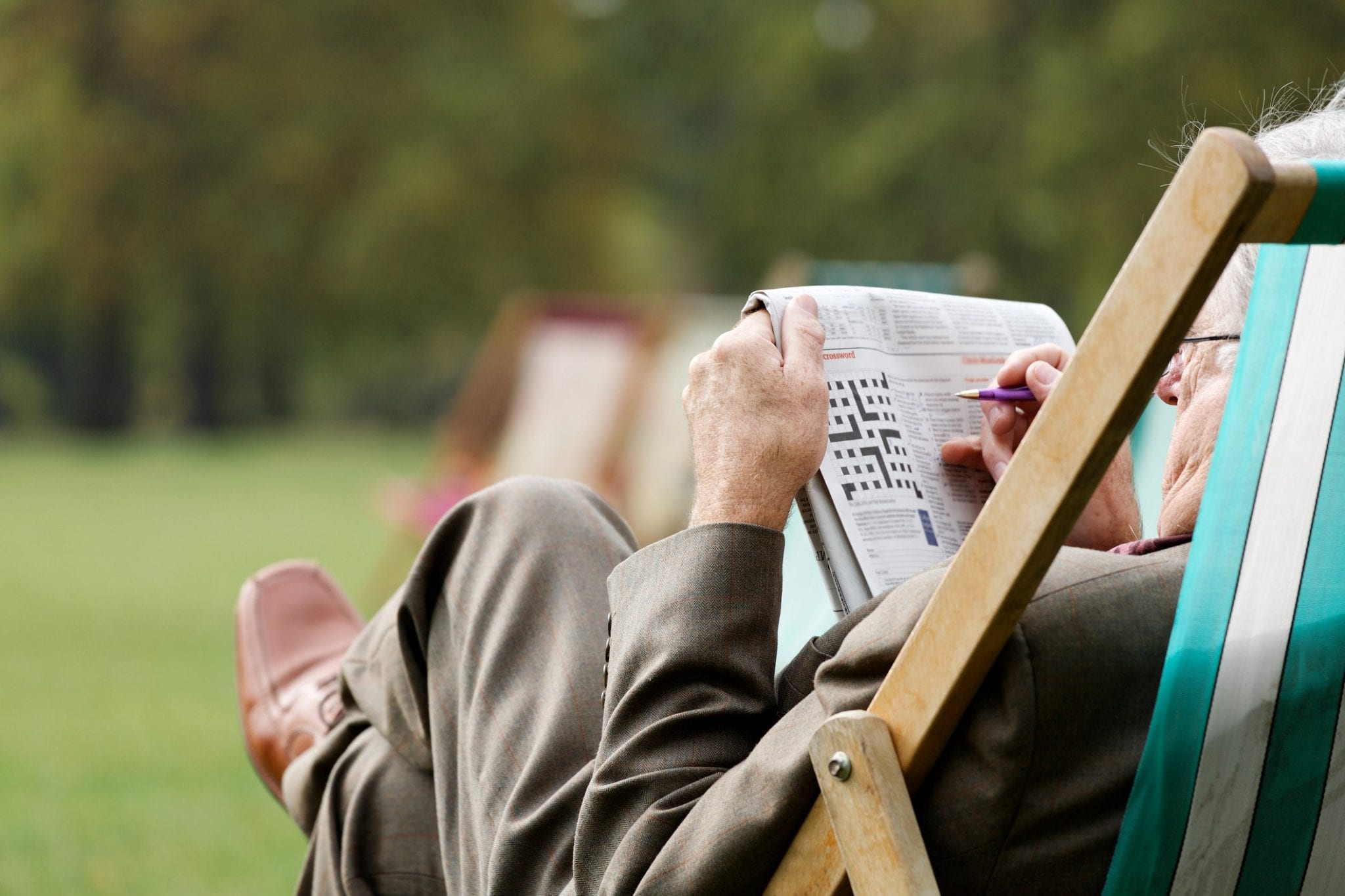 senior doing crossword in park to keep mind young