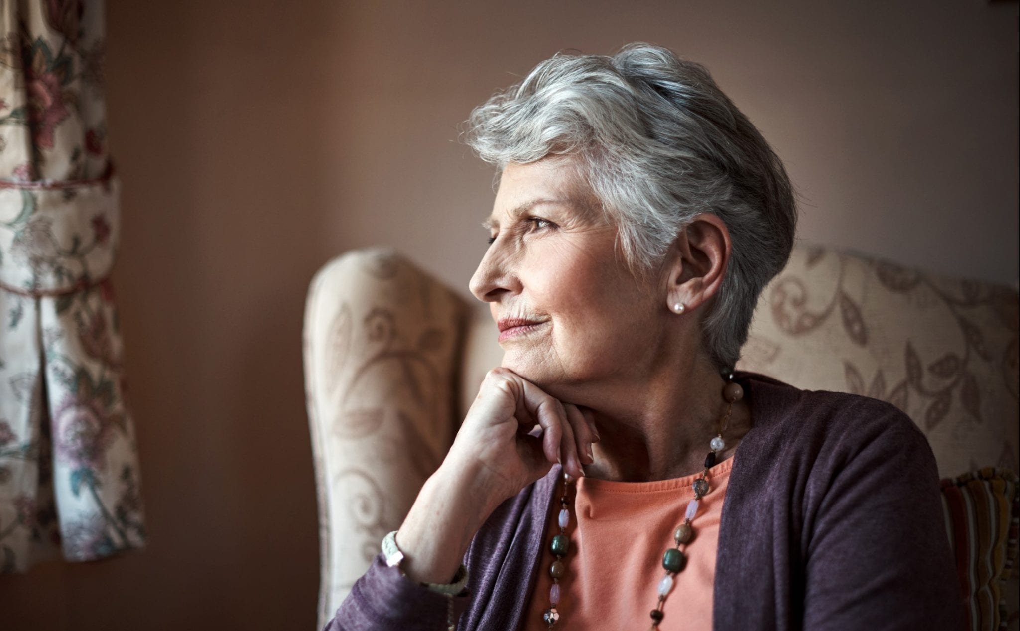 moving your parent out of a nursing home may cause stress. Worried Senior woman looking out a window