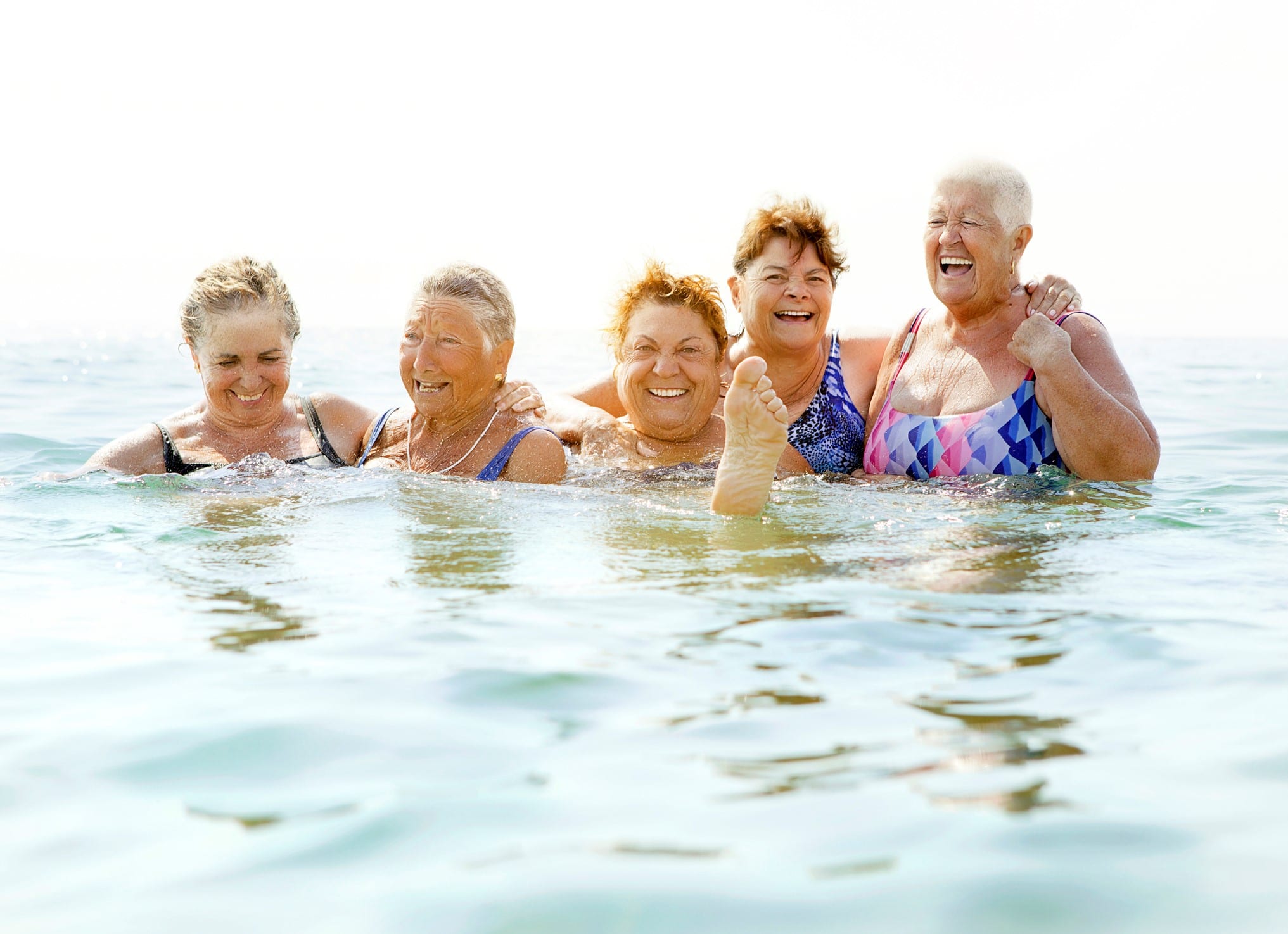 happy senior women splashing in cool lake