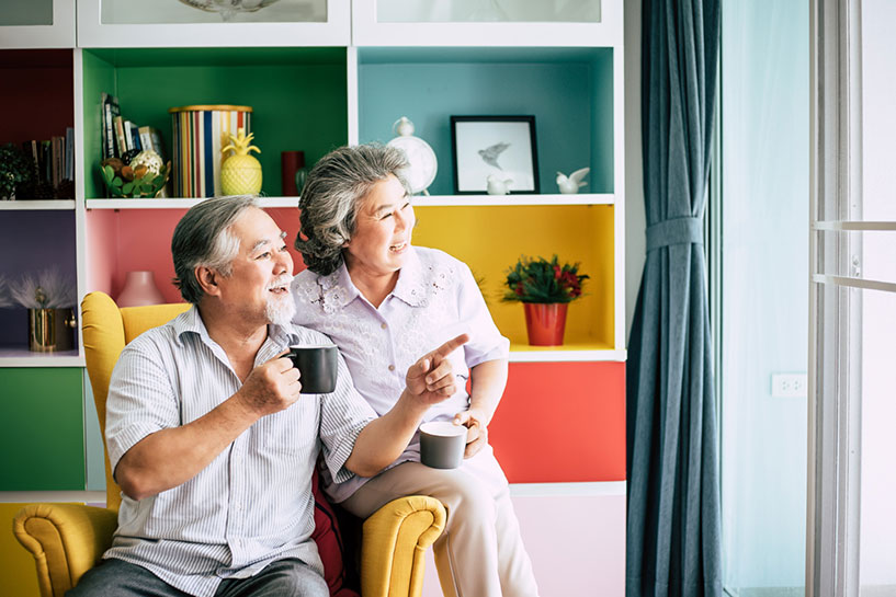 Senior couple smiling and looking outside with mugs in hands