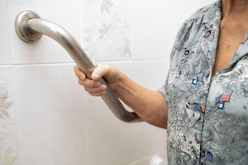 Senior woman holding on to grab bar in the bathroom