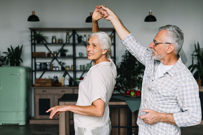 Happy senior couple dancing in the kitchen. Fall prevention.