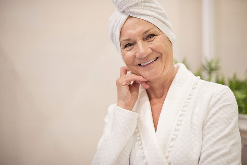 Senior woman in bath robe & towel after using a portable shower