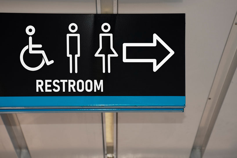 Public sign pointing to restroom and showing availability of accessible bathrooms