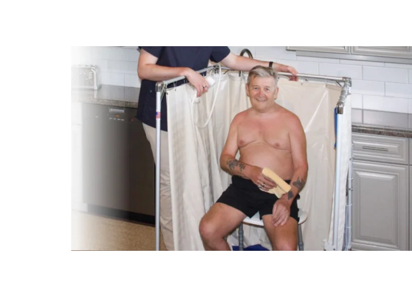 Man getting help showering in temporary Portable Indoor Showers that is accessible to wheelchairs