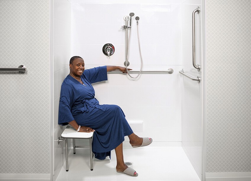Woman in a Roll in Accessible Shower stall in her home with a Barrier Free threshold