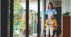 senior in wheelchair inside retirement home with nurse