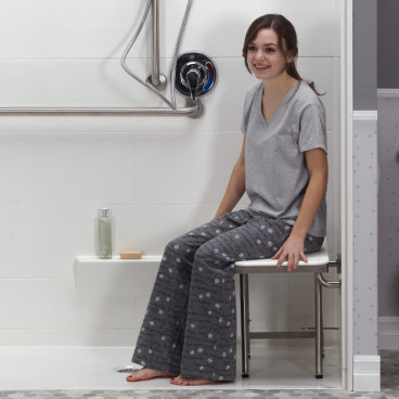 Female in pjs sitting on white ADA shower seat in shower